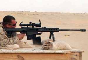 Side profile view of a Barrett M107 being fired by a soldier in the desert